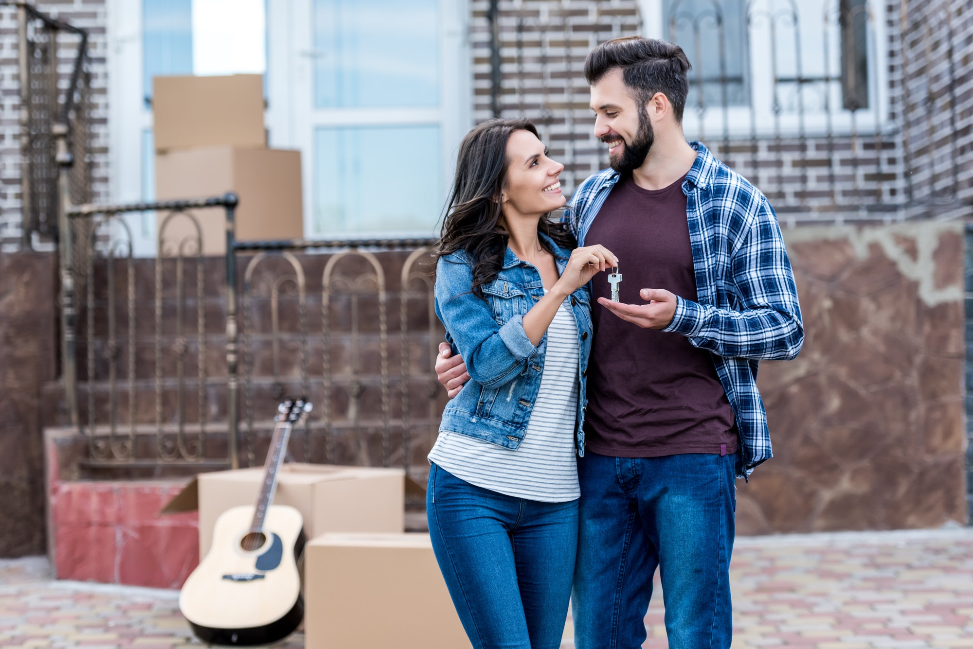 young beautiful couple with keys in front of new house